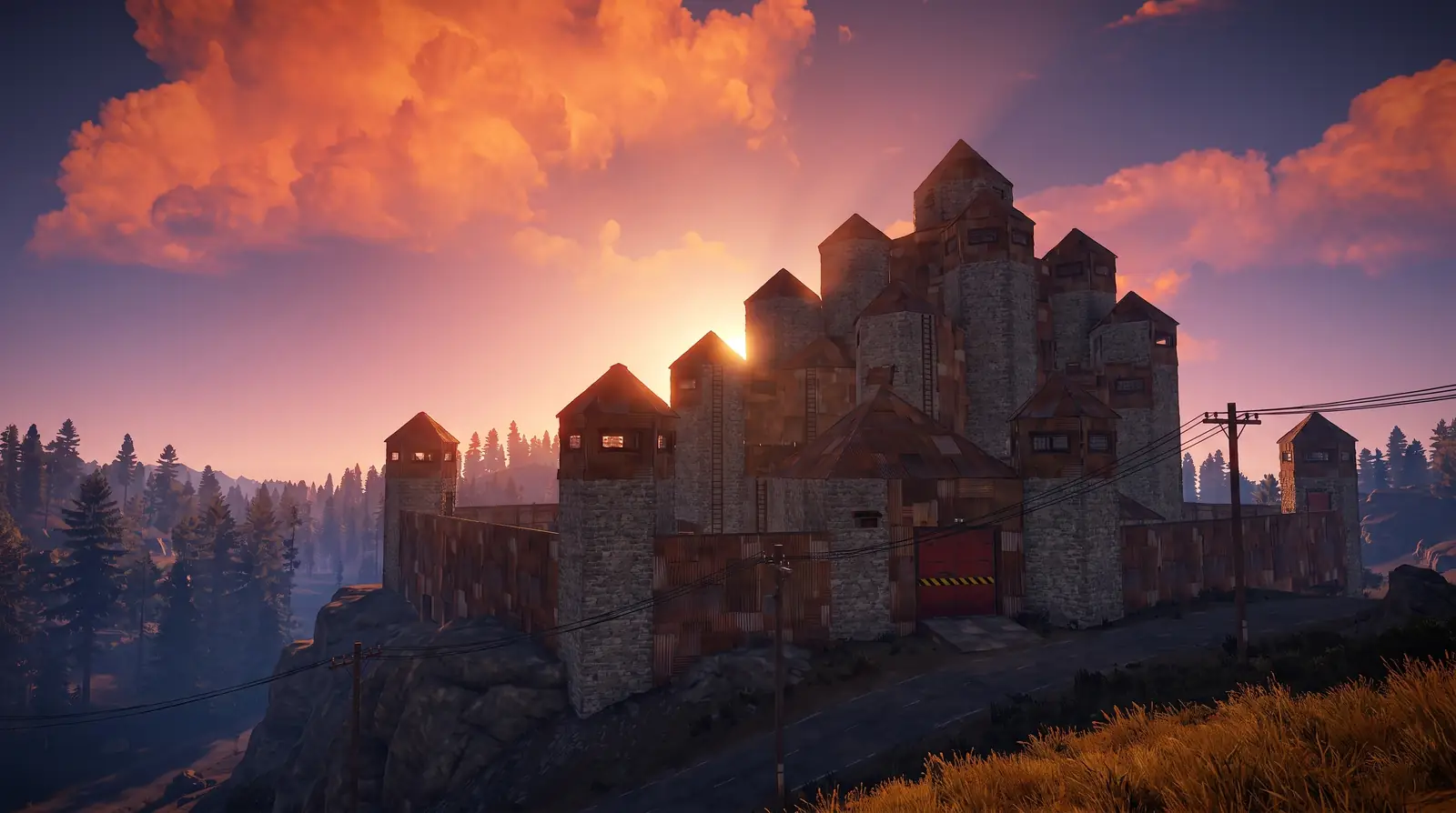 A sprawling player-built fortress on a rocky ridge at dusk, radio towers and a distant refinery behind it.